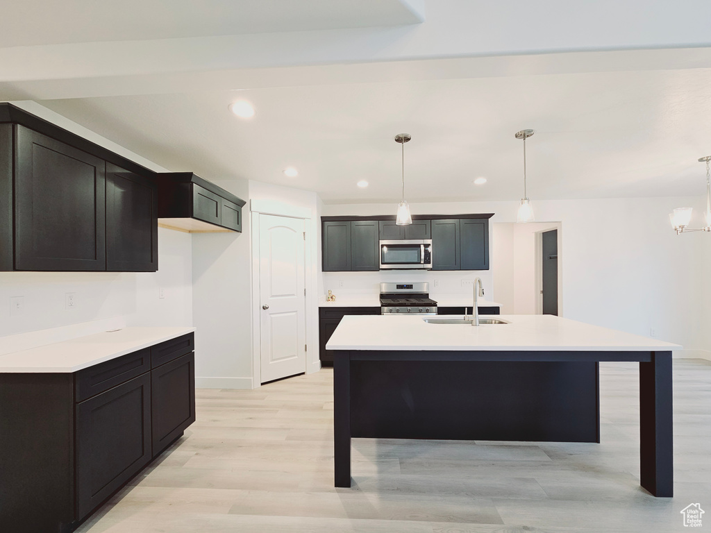 Kitchen with appliances with stainless steel finishes, a sink, pendant lighting, light countertops, and recessed lighting