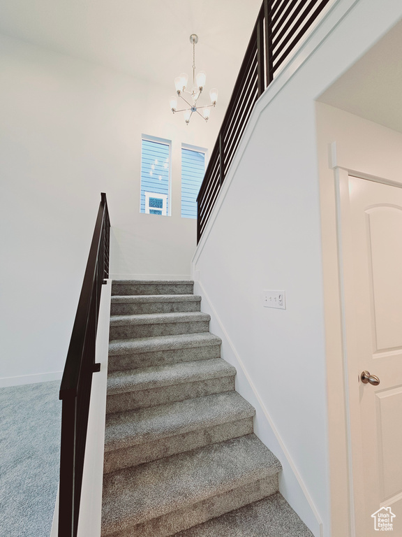 Stairway with carpet, a chandelier, and baseboards