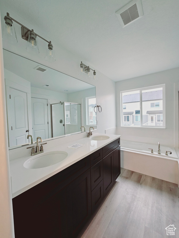 Bathroom with wood finished floors, double vanity, a garden tub, and a shower stall