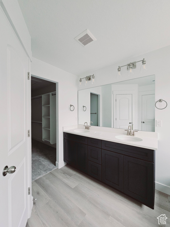 Bathroom with wood finished floors, double vanity, and baseboards