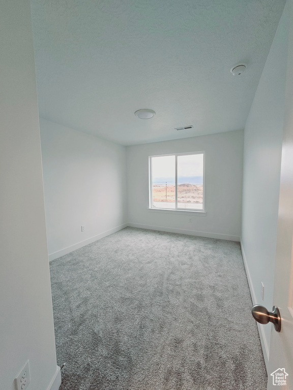 Carpeted spare room featuring baseboards