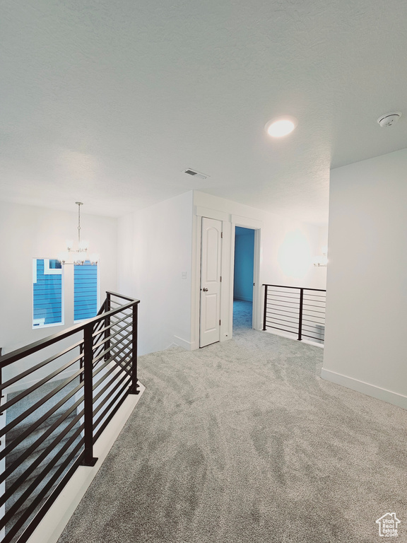 Spare room with a chandelier, carpet flooring, a smoke detector, and baseboards