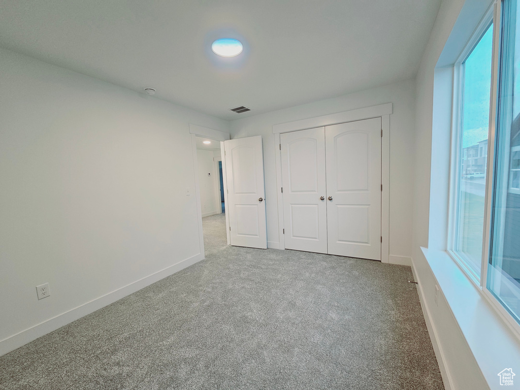 Unfurnished bedroom with carpet flooring, baseboards, and a closet