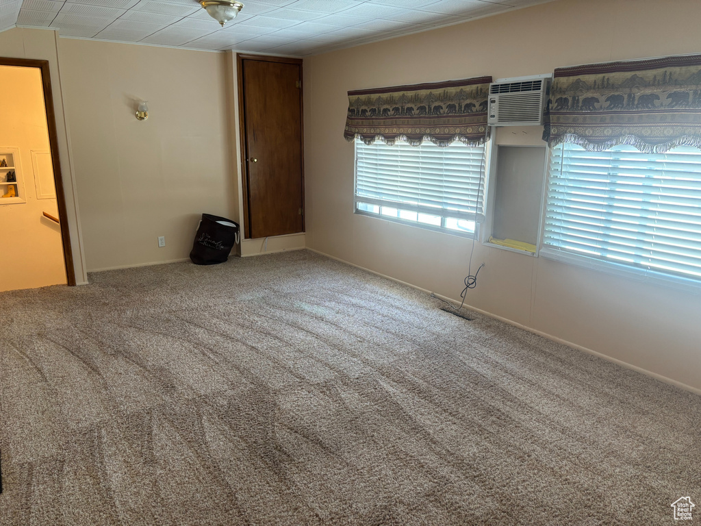 Empty room featuring carpet flooring and an AC wall unit