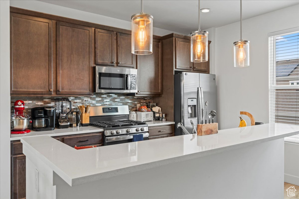 Kitchen with stainless steel appliances, light countertops, and tasteful backsplash
