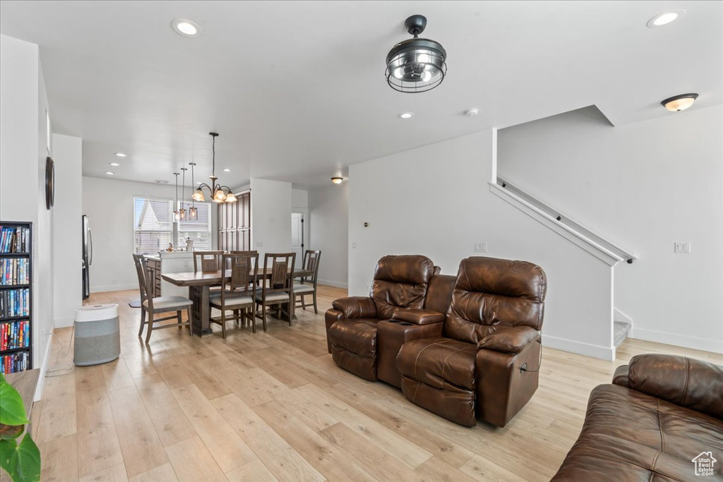 Living area featuring light wood-style flooring, stairs, baseboards, a chandelier, and recessed lighting
