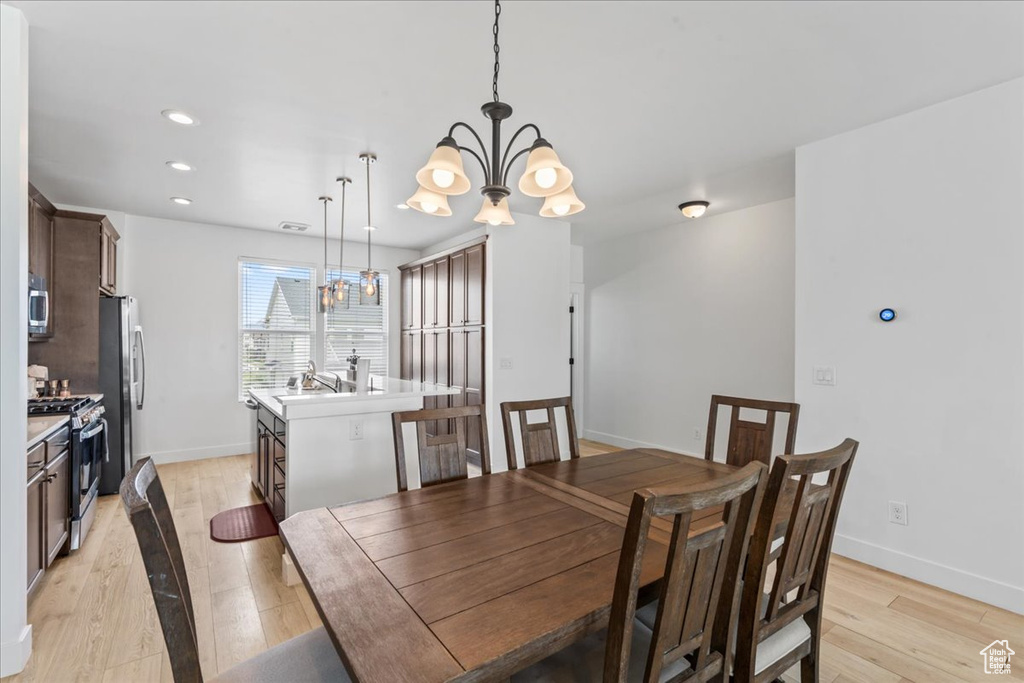 Dining room with a chandelier, light wood-type flooring, baseboards, and recessed lighting