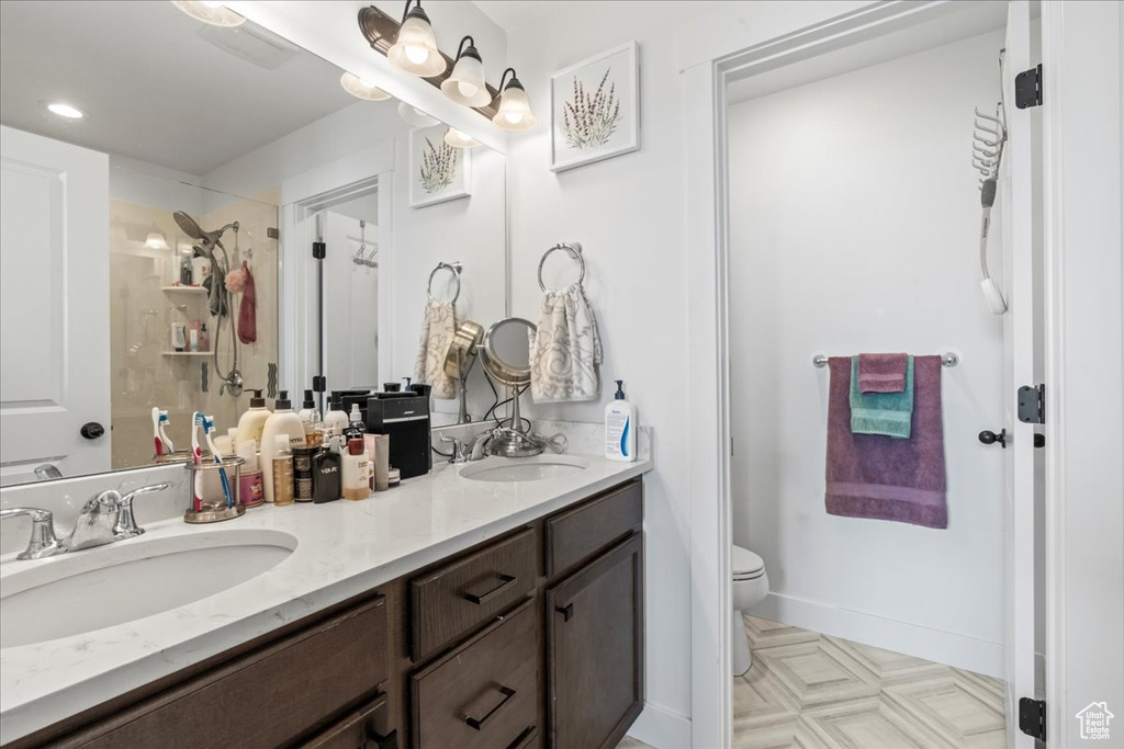 Bathroom with double vanity, toilet, a shower, and recessed lighting