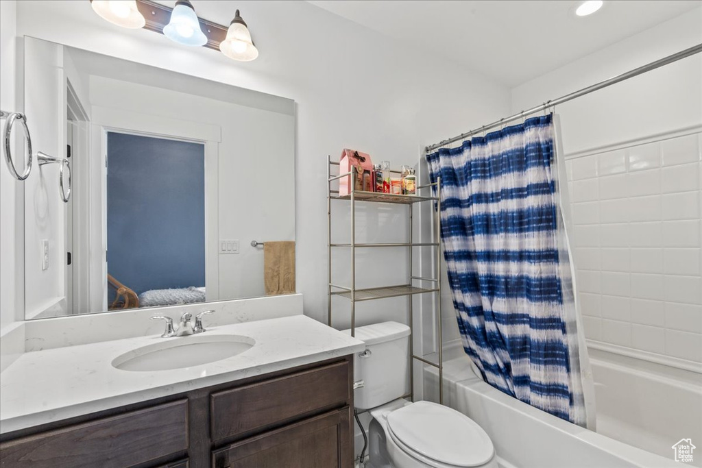 Full bath with vanity, shower / bathtub combination with curtain, toilet, and connected bathroom
