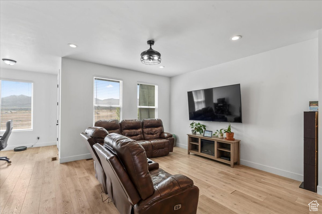 Living room with light wood finished floors, baseboards, and recessed lighting