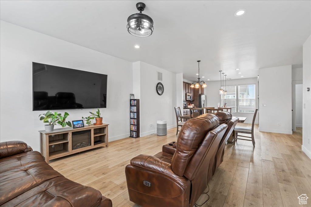 Living room featuring light wood-style floors, baseboards, a chandelier, and recessed lighting