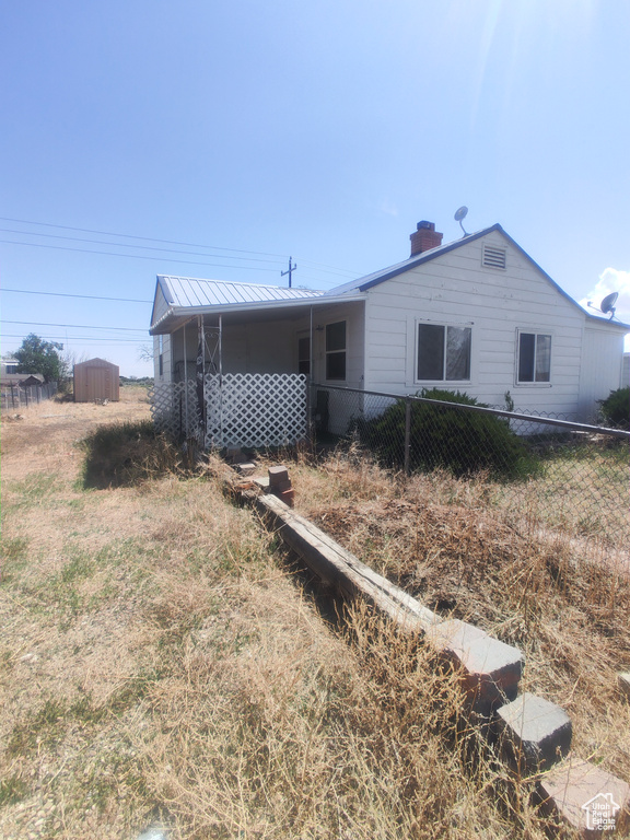 View of front of house featuring a chimney and metal roof