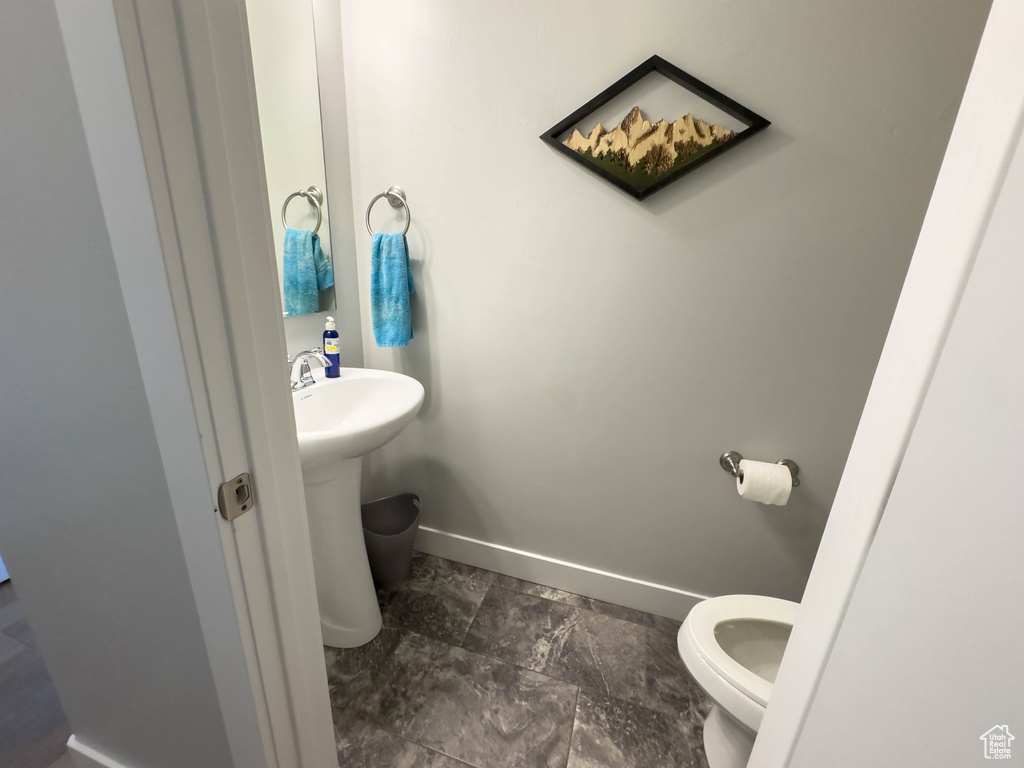 Bathroom with toilet, baseboards, and a sink