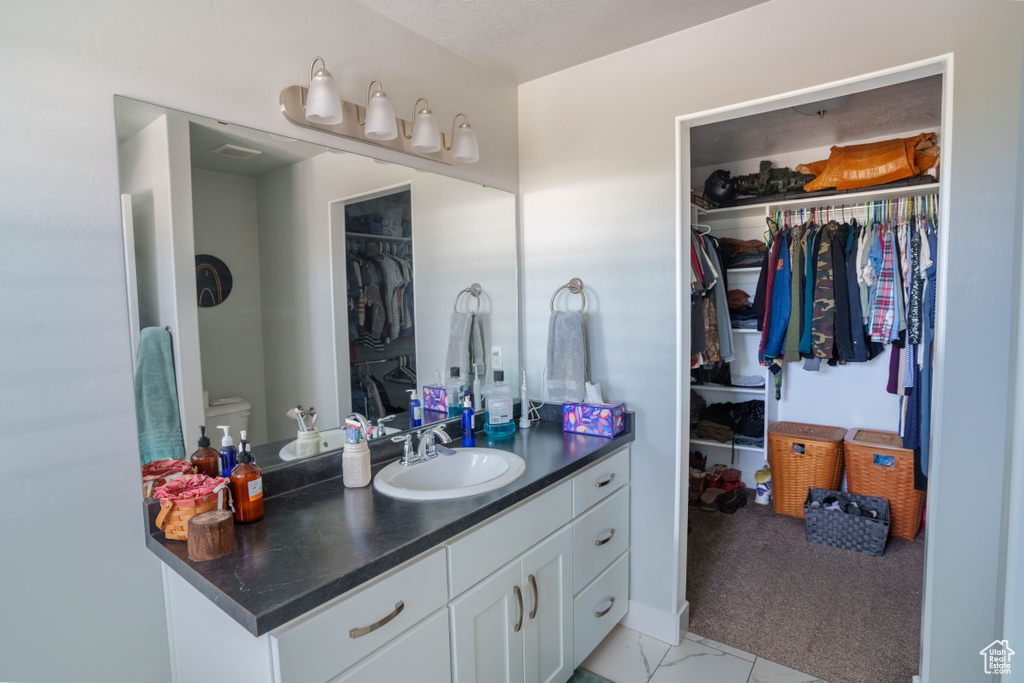 Bathroom with vanity, toilet, and a walk in closet