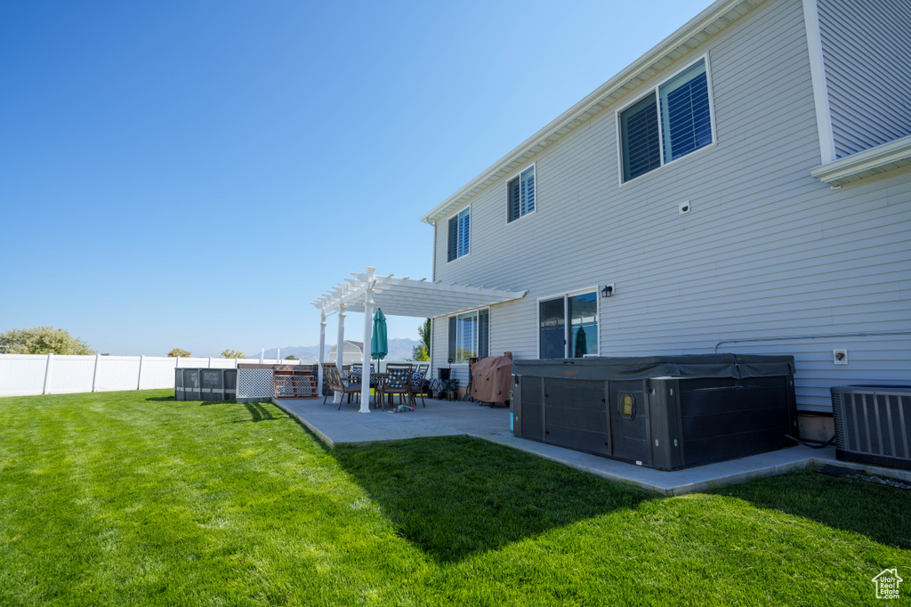 Back of property with a hot tub, a pergola, a patio area, and central air condition unit