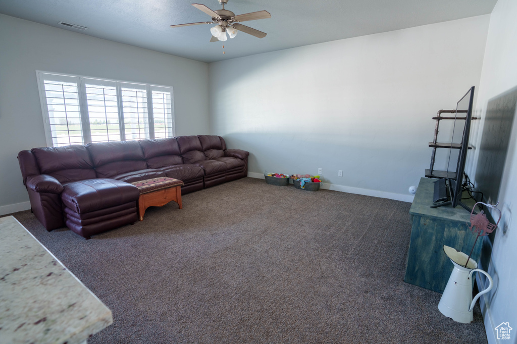 Living room with ceiling fan, carpet, and baseboards