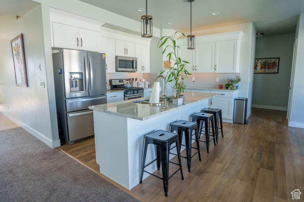 Kitchen featuring appliances with stainless steel finishes, a sink, baseboards, white cabinetry, and recessed lighting