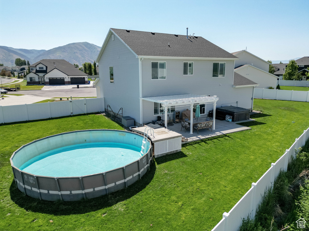Rear view of house with a mountain view, a pergola, a hot tub, and a patio area