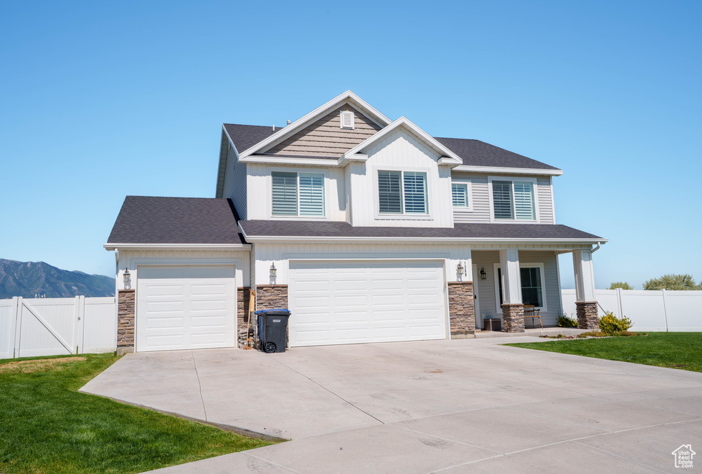 Craftsman house featuring concrete driveway, stone siding, a porch, and a mountain view