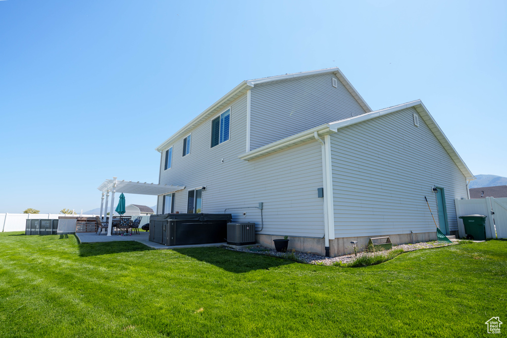 Rear view of property with a hot tub, a pergola, a patio, and central AC