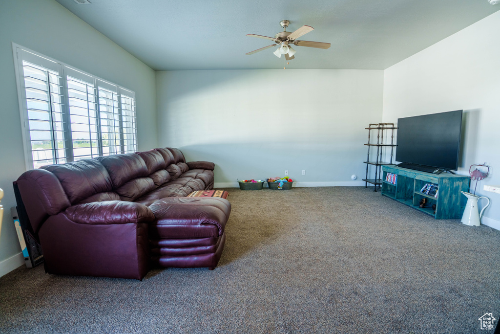 Living area with carpet flooring, a ceiling fan, and baseboards