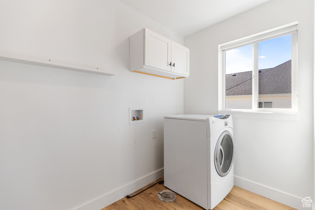 Laundry area featuring washer / clothes dryer, cabinet space, baseboards, and light wood finished floors