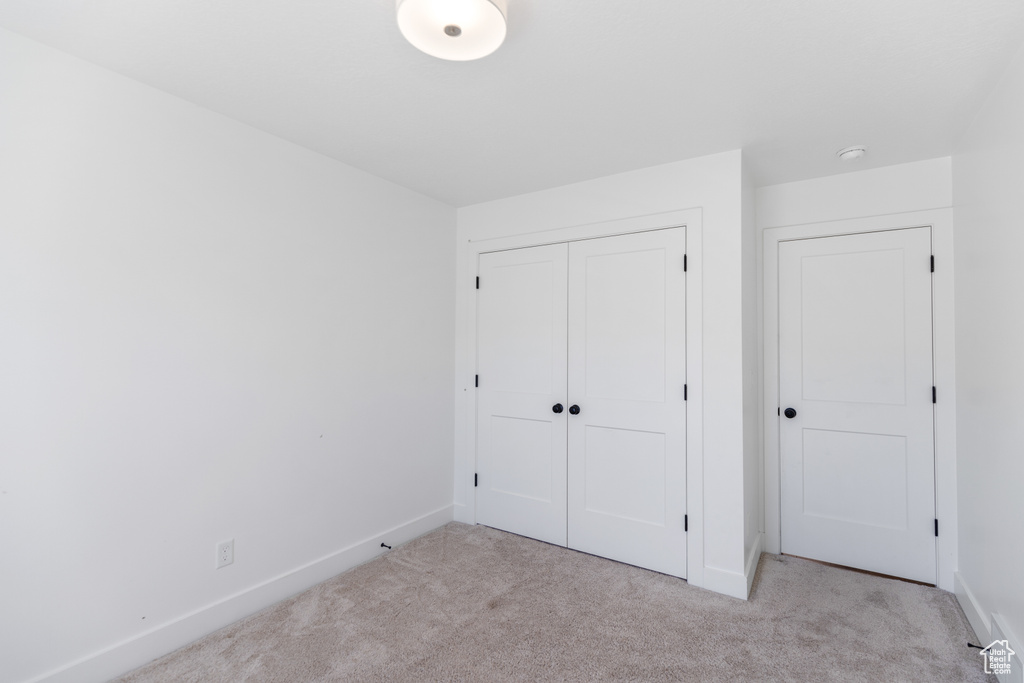 Unfurnished bedroom with carpet flooring, baseboards, and a closet
