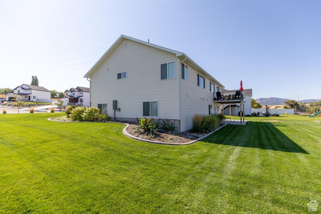 Back of house featuring a yard and a deck with mountain view