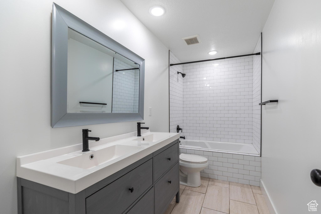 Bathroom with double vanity, toilet, tiled shower / bath combo, and recessed lighting