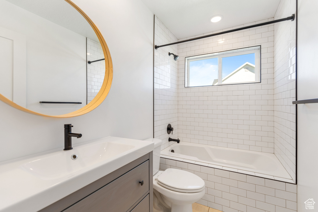 Full bathroom featuring tiled shower / bath combo, toilet, vanity, and recessed lighting