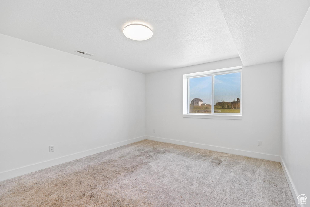 Carpeted spare room featuring baseboards