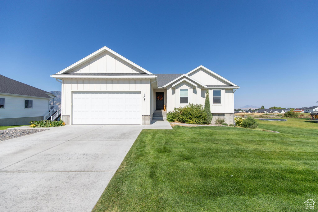 Single story home with a garage, board and batten siding, concrete driveway, and a front lawn