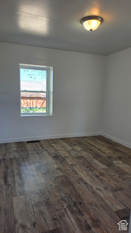 Spare room featuring dark wood-style floors and baseboards