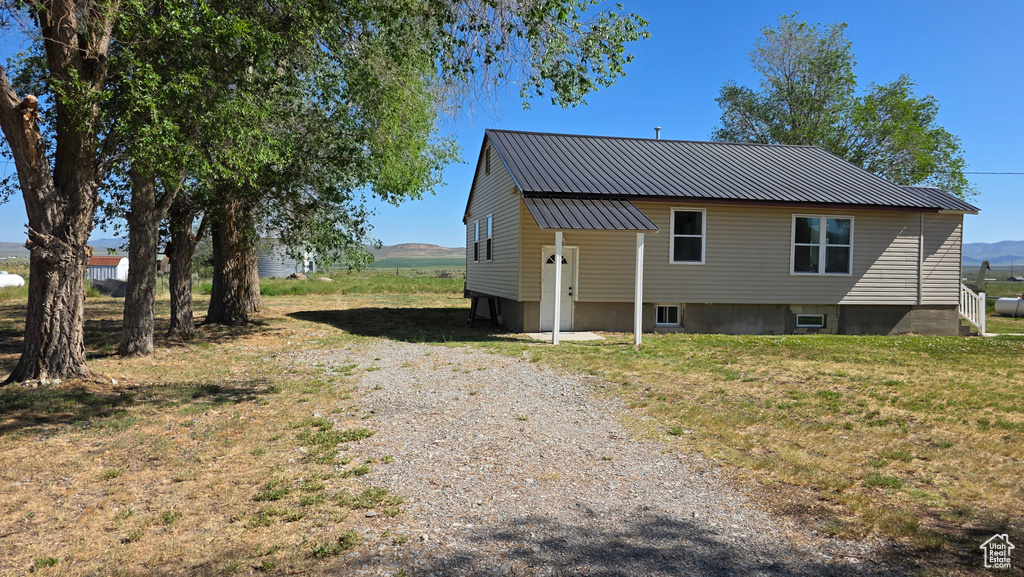 Rear view of house with gravel driveway and metal roof