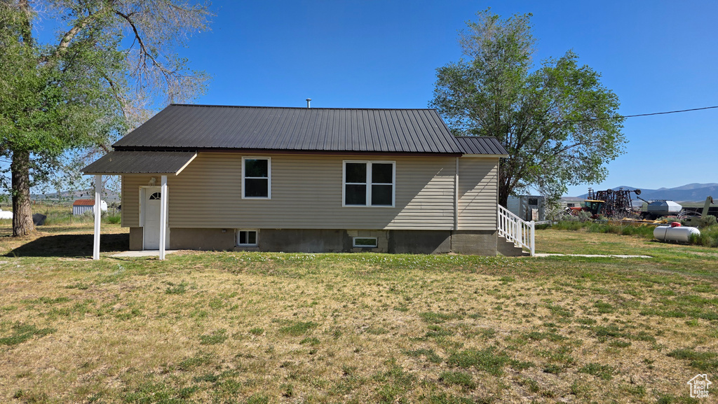 Back of house with metal roof and a yard