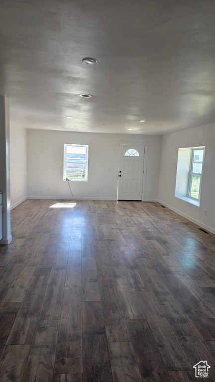 Empty room featuring dark wood-style flooring, healthy amount of natural light, baseboards, and recessed lighting