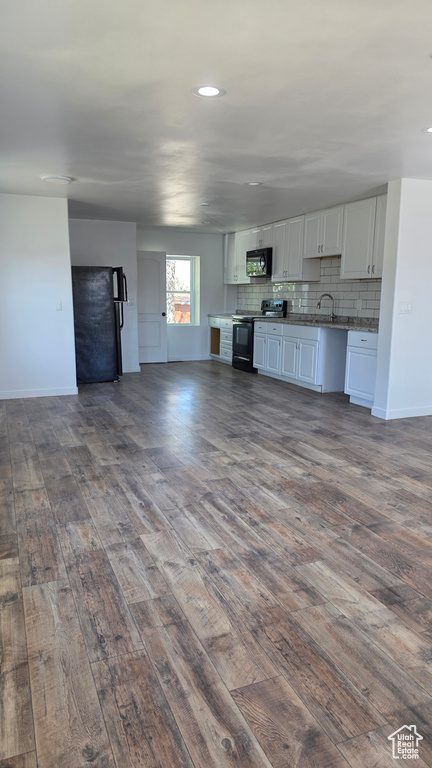 Unfurnished living room featuring dark wood finished floors, baseboards, recessed lighting, and a sink