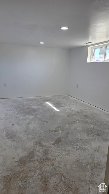 Empty room with unfinished concrete flooring and recessed lighting