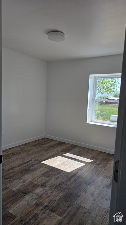 Empty room featuring dark wood-style floors and baseboards