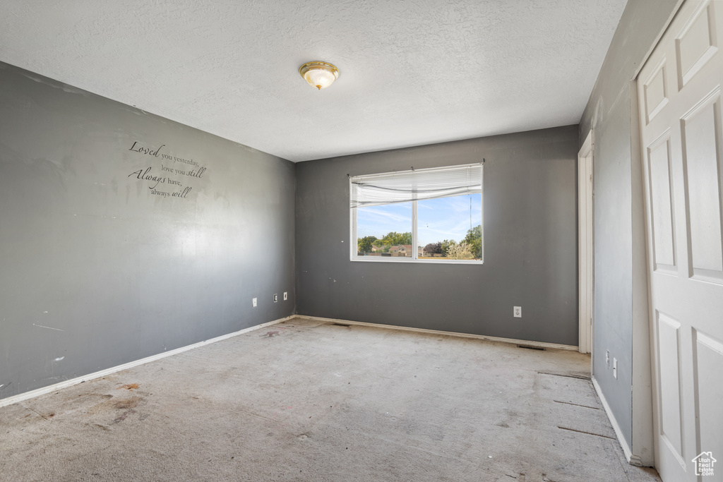 Unfurnished bedroom with a textured ceiling, carpet, and baseboards