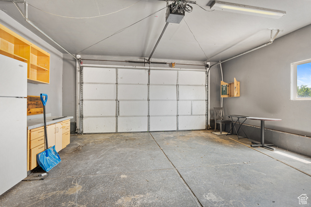 Garage featuring freestanding refrigerator and a garage door opener