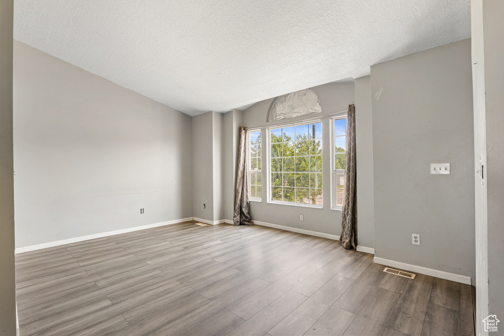 Spare room with wood finished floors, a textured ceiling, and baseboards