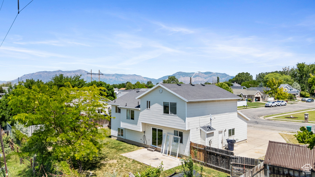 Back of property with a patio, a shingled roof, and a mountain view