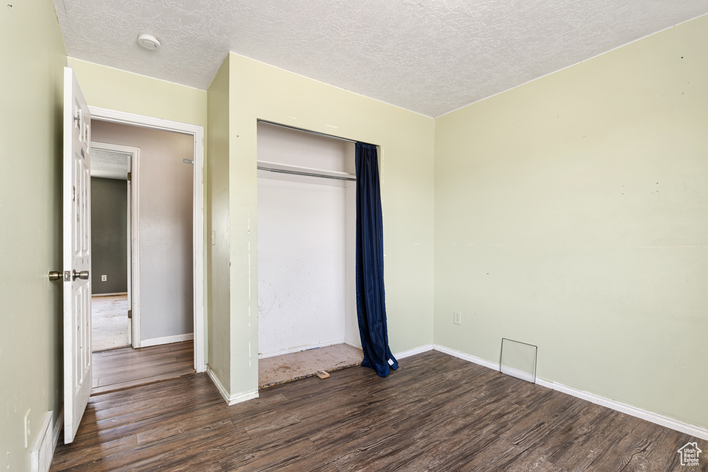 Unfurnished bedroom featuring wood finished floors, a textured ceiling, a closet, and baseboards