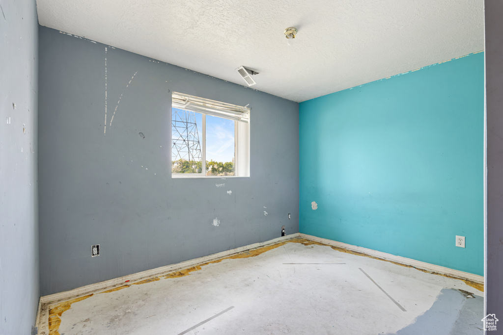 Empty room with a textured ceiling and baseboards