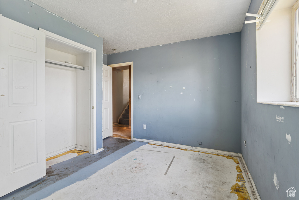 Unfurnished bedroom with a textured ceiling, a closet, and baseboards