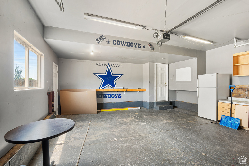 Garage with freestanding refrigerator and a garage door opener