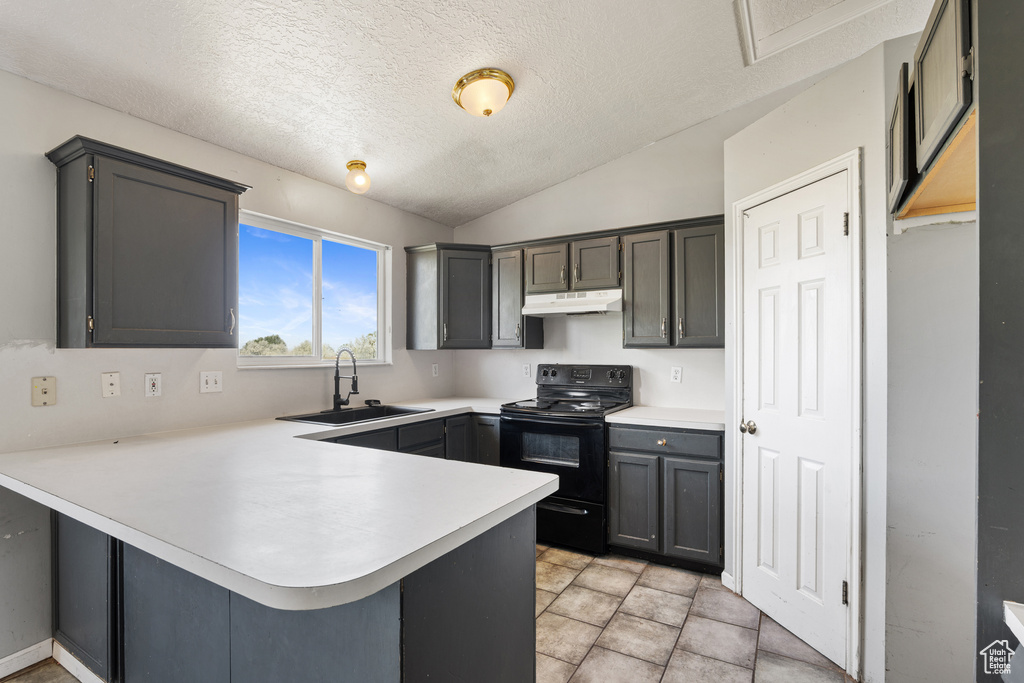Kitchen featuring electric range, a sink, under cabinet range hood, a peninsula, and light countertops