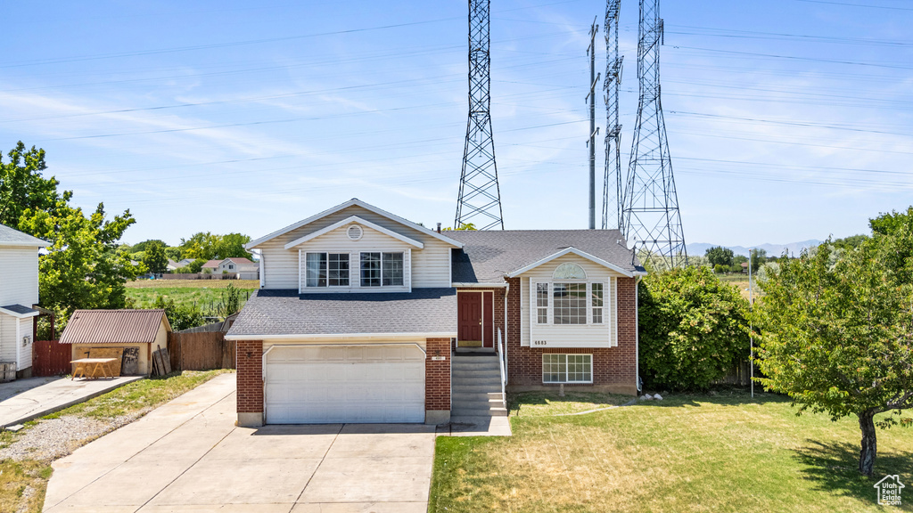 View of front facade with brick siding, an attached garage, a front yard, and driveway