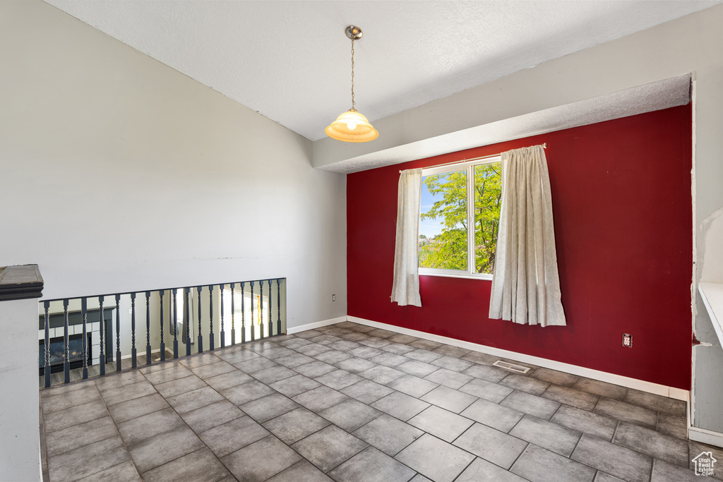 Unfurnished room featuring baseboards and lofted ceiling